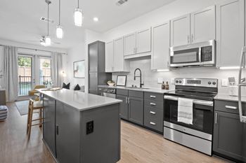 a kitchen with stainless steel appliances and white cabinets at Abstract at Design District, Dallas, TX, 75207